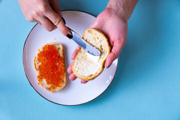 Recipe for making a sandwich with red caviar. Step by step, the girl spreads butter on the bread