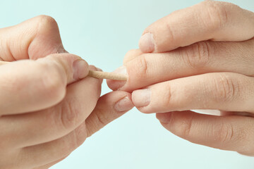 Cuticle treatment with an orange stick during a nail edging manicure. The girl makes a manicure at home. Cuticle treatment with an orange stick on an isolated background. Close-up.