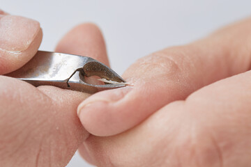 Treatment of the cuticle with forceps during the edged nail manicure. The girl makes herself an...