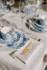Table setting with vintage porcelain tableware, mimosa flowers and wine glasses.