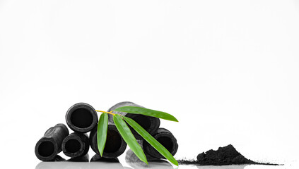Bamboo activated charcoal sticks green leaf and coal powder isolated on white background