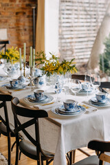 Table setting with vintage porcelain tableware, mimosa flowers and candles.