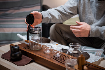 The process of tea ceremony at home. The tea master puts pieces of raw aged black tea in a teapot on a bamboo tray