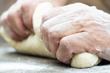 a man kneads dough with his hands on the table