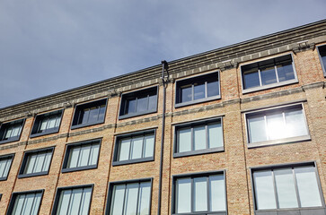 Brick building with windows and downspout against blue sky