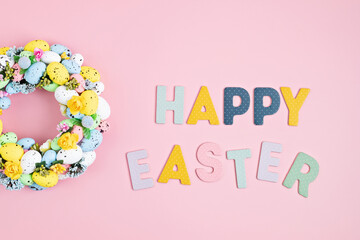 Handmade diy home interior decoration wreath with colorful easter eggs over pink background