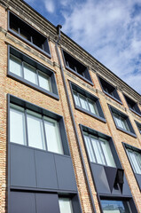 Fototapeta na wymiar Brick building with windows and downspout against blue sky