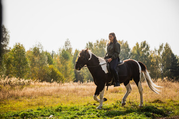 Cute girl equestrian instructor rides a horse in an equestrian club.