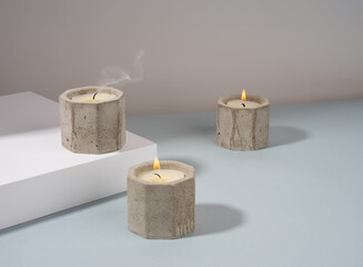 Creative diagonal isometric projection. Composition with scented candles of soy wax in a concrete candlestick on a blue and white background. Minimalism. Shadow. Natural material.