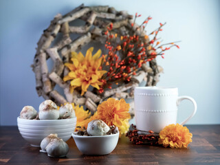 Cappuccino cake balls, coffee flavored truffle like dessert, decorated with fall orange flowers on a wooden table with white ceramic coffee mug and bowls.