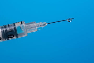A drop of vaccine on a syringe needle close-up.