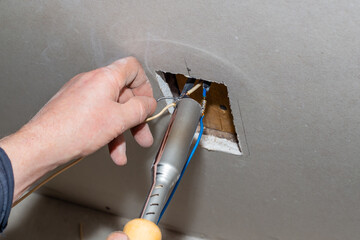 The electrician solders the twisted electrical wires in the socket with a belt. Installation of...