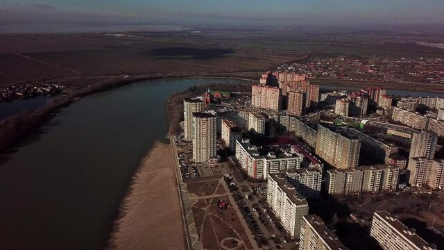 aerial panorama of the embankment of the bend of the Kuban River and a microdistrict with a typical development of multi-storey buildings, which is an Orthodox church with golden domes on a sunny day