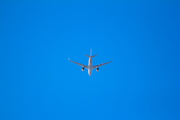Fototapeta na wymiar Airplane flying in clear blue sunny weather