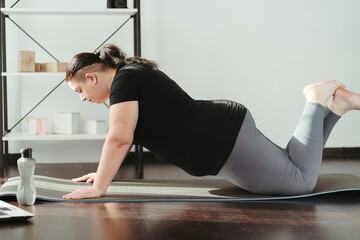 Fitness, home training. Overweight woman doing push-ups and looking on laptop in living room, online training class