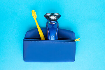 Men's electric razor and toothbrush in a travel case on a blue background, top view.