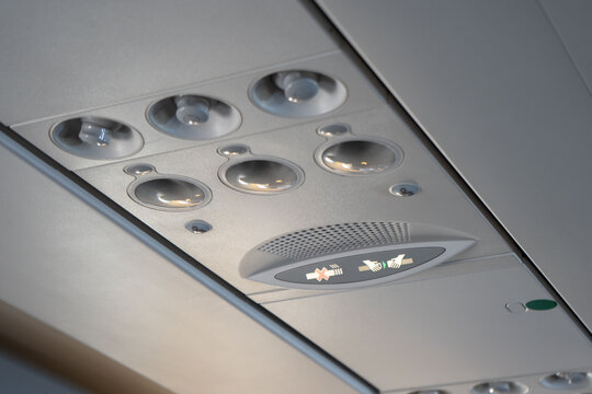 Overhead lights, air conditioning and safety signs in the plane cabin