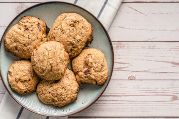 Close up top view on crunchy oatmeal chip cookies fresh baked biscuits with chocolate and cocoa in a plate on the table - homemade food concept copy space