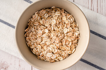 Close up top view on oat rye and wheat flakes in a bowl - vegan or vegetarian organic food concept