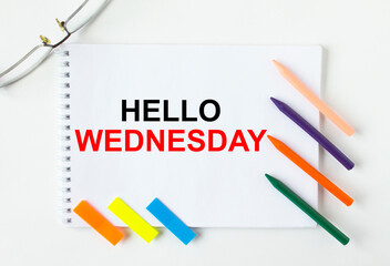 Notepad with text Hello Wednesday glasses colored pencils and colored stickers