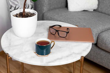 A cup of tea, a computer and glasses on a light coffee table. High quality photo