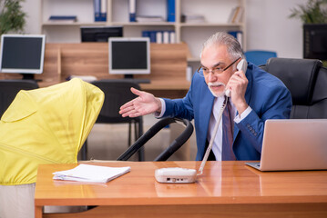 Aged businessman employee looking after newborn at workplace