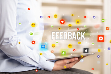 Close up of business person playing multimedia with social media icons and FEEDBACK inscription