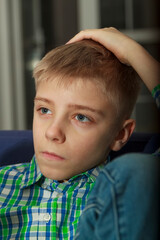 Young boy watch television in living room. Kid with blue eyes while watching TV. Сlose up view