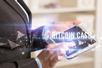Close up hands using tablet with BITCOIN CASH inscription, modern business technology concept