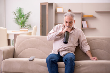 Obraz premium Old man drinking alcohol at home