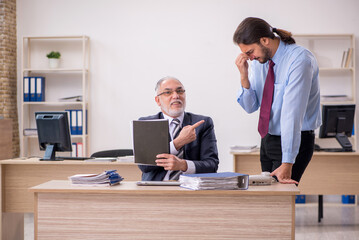 Old male boss and young employee working in the office