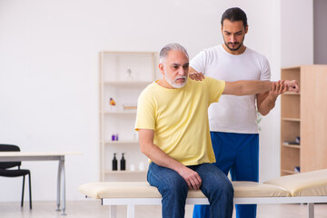 Obraz premium Old male patient visiting young male doctor chiropractor
