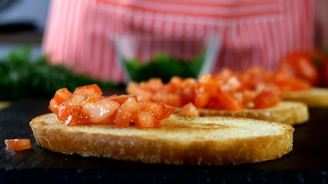 Chef sprinkles finely chopped red tomatoes of toas