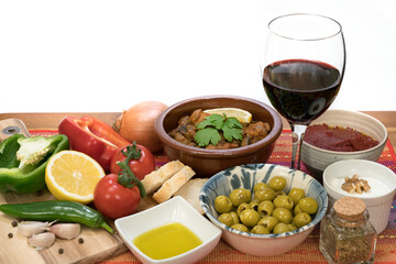 Mediterranean food - cooked meat, olives, yogurt, vegetables,  olive oil, wine - on a wooden table and white background