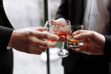 Business meeting. Men hold glasses of whiskey. Men's Party. Hand with a drink of alcohol