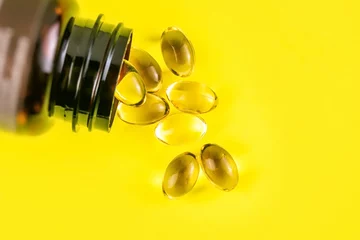 Foto auf Acrylglas K2 Container spill with Omega-3 and Vitamin D3 capsules
