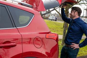 車のバックドアを開けて中を確認する白人男性
