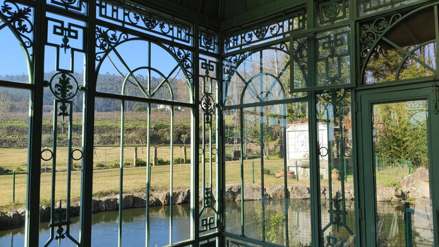 Inside traditional old greenhouse structure in the elegant large botanical garden on a large mansion estate near Esposende, Portugal. Cute small greenhouse in a private Garden and pond.