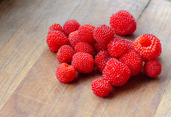 Fresh, wild and ripe raspberries on  a wooden background . Close up photography.