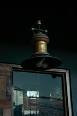 An old lamp attached to the ceiling and under the shadows.
