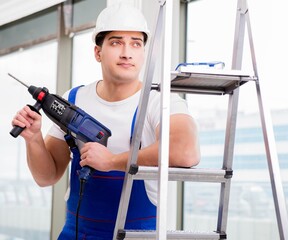 Repairman working with power drill in workshop