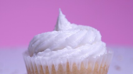 Decorated colourful cupcake for the holiday, shallow depth of field. Close up macro focus on the iced muffin. Pink background. Presentation of delicious desserts at anniversary or birthday.