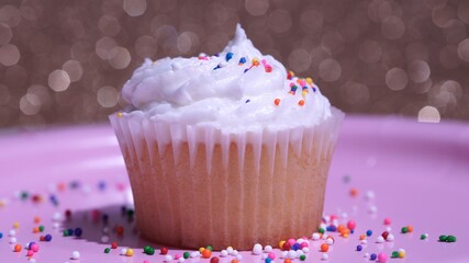 Cupcake macro shallow depth of field and decoration with sugar sprinkles. Cup cake with white vanilla cream on gold background. Process of making delicious desserts muffin for delivery or sale.
