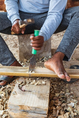 Worker chiseling bamboo at a boatyard in Oman.