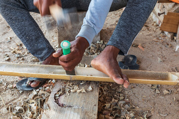 Worker chiseling bamboo at a boatyard in Oman.