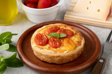 Homemade caprese quiche over wooden plate with ingredients