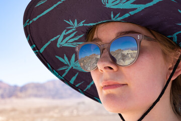 Close-up portrait of girl with glasses reflecting Zabriskie Point