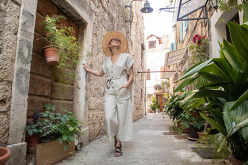 Beautiful blonde young female traveler wearing straw sun hat sightseeing and enjoying summer...