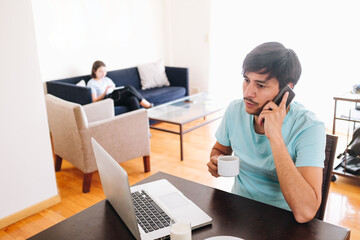 young workaholic talking on the phone while having breakfast