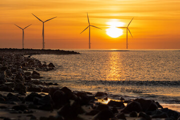 Wind turbines seascape at summer sunrise with calm sea